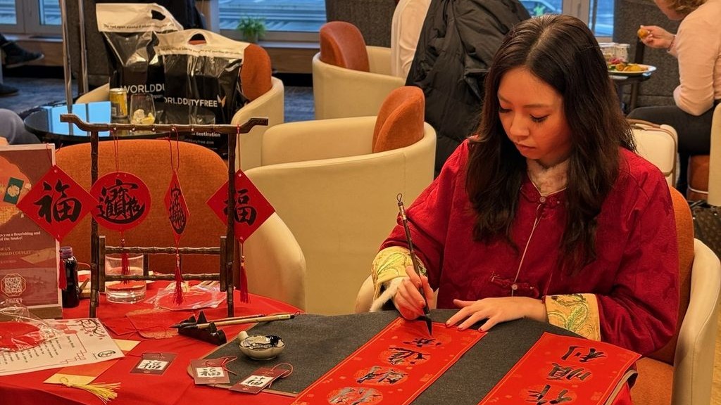 A woman in red producing Chinese calligraphy 