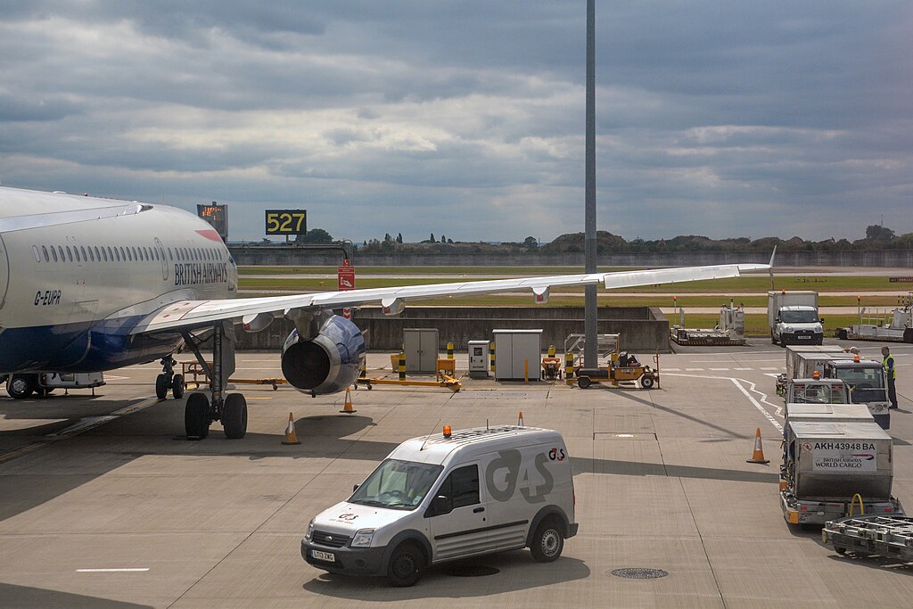 Aircraft on the London Heathrow Airport's tarmac; a van in the foreground. 