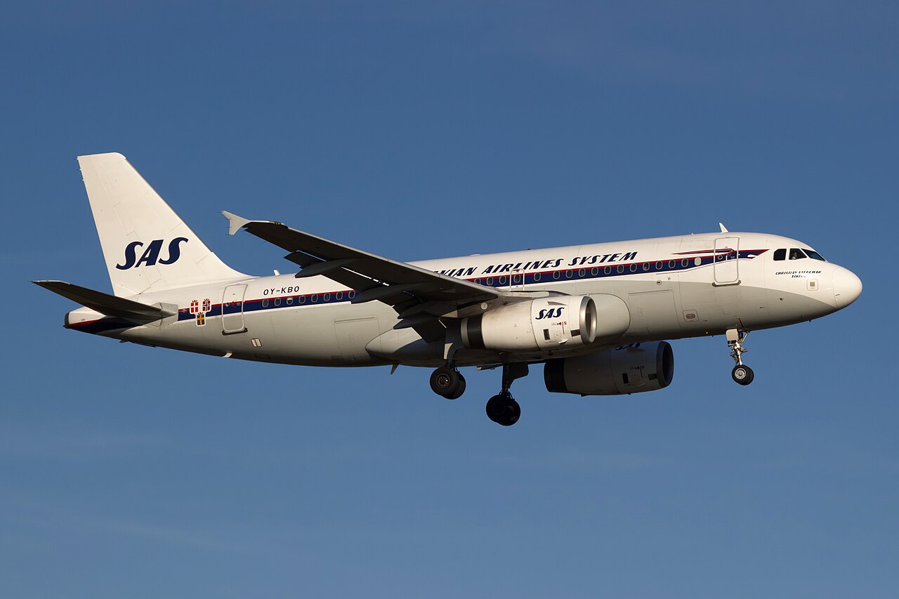 Scandinavian Airlines A319 with a retro livery flying under a blue sky