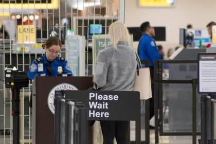 A Transportation Security Administration agent at a checkpoint verifying passenger identification, at the John Glenn Columbus International Airport.