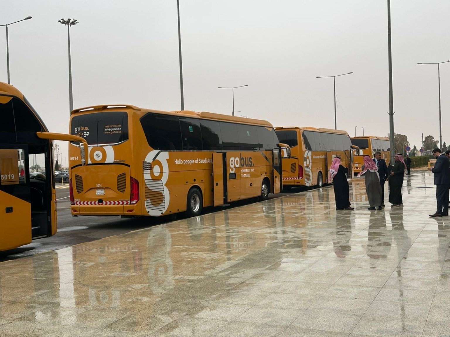 A line of coaches parked outside an airport terminal.