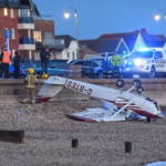 A light aircraft lying upside-down on a beach