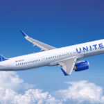United Airlines plane in sky between blue skies and some clouds below.