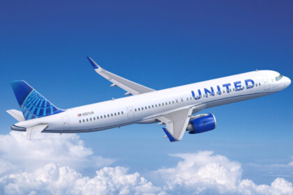 United Airlines plane in sky between blue skies and some clouds below.