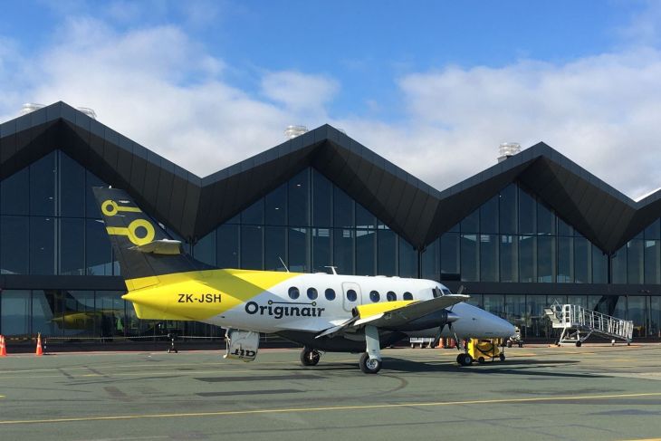 Originair aircraft landed in front of gates under a blue sky