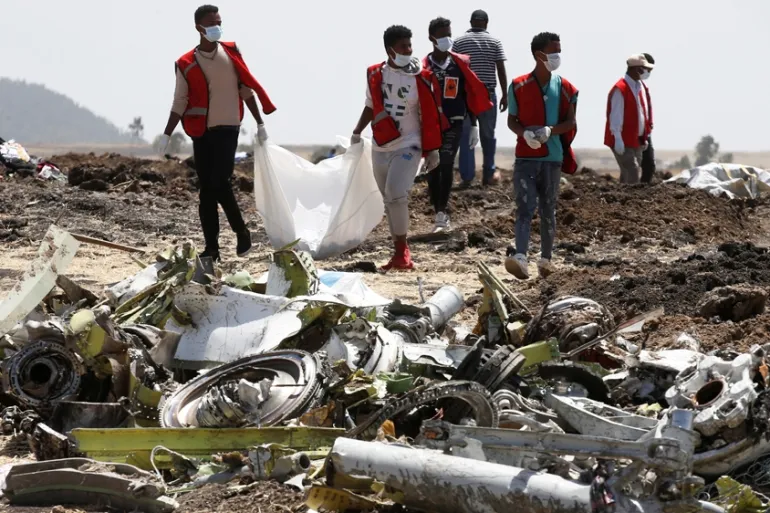 Rescue and investigation personnel walk among debris at the Ethiopian Airlines Flight 302 crash site