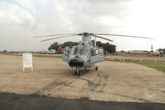 A head-on view of a light grey Harbin Z-9EH military helicopter parked on a tarmac under an overcast sky.