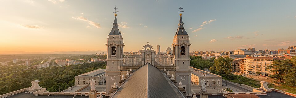 A sunset view from the dome of Almudena Cathedral looking toward its two towers with the Royal Palace of Madrid in the background