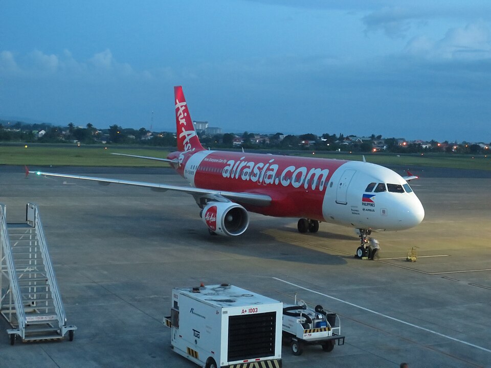 A high-angle, eye-level shot captures a Philippines AirAsia Airbus A320-216 parked on an airport tarmac during the early evening.