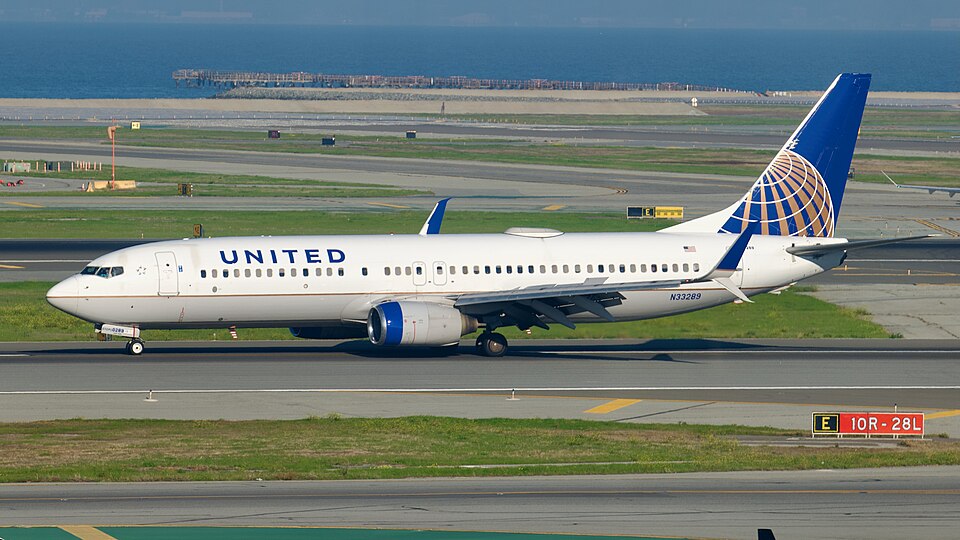 Side-profile view of a white United Airlines Boeing 737-800 taxiing on an airport tarmac.