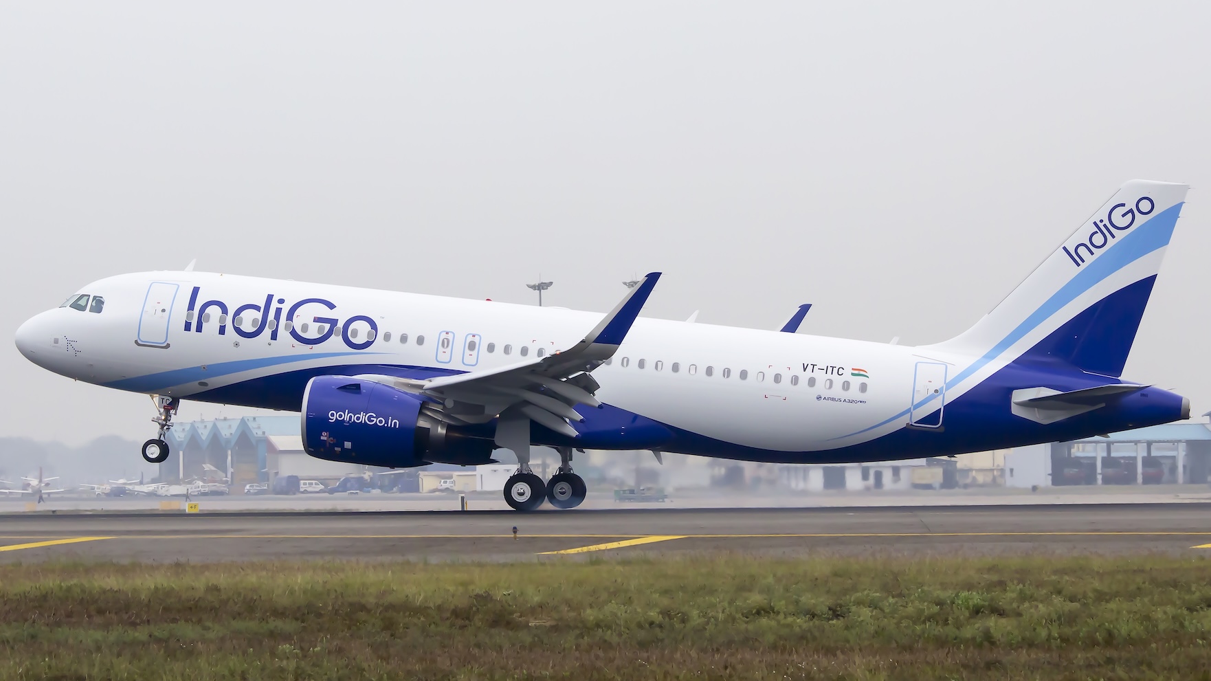 An IndiGo Airbus 320 neo aircraft on the runway amid cloudy skies.