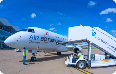 A white passenger plane sitting on the tarmac at an airport with a man in front of it
