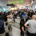A crowd of people waiting inside a busy airport
