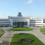 Original passenger terminal at Dublin Airport, a white pre-war International-style building; grass on the foreground; blue sky.