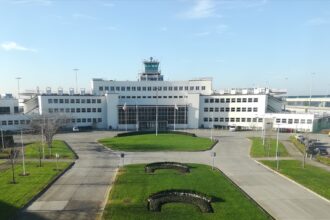 Original passenger terminal at Dublin Airport, a white pre-war International-style building; grass on the foreground; blue sky.