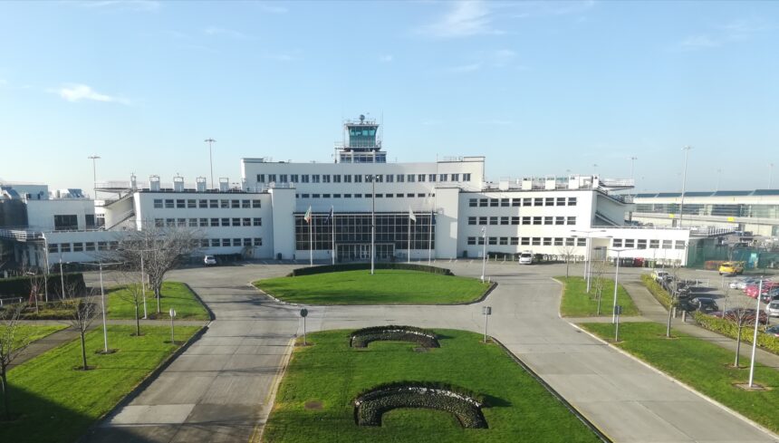 Original passenger terminal at Dublin Airport, a white pre-war International-style building; grass on the foreground; blue sky.
