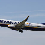 Ryanair Boeing 737 flying in blue sky; dispersing clouds in the background.