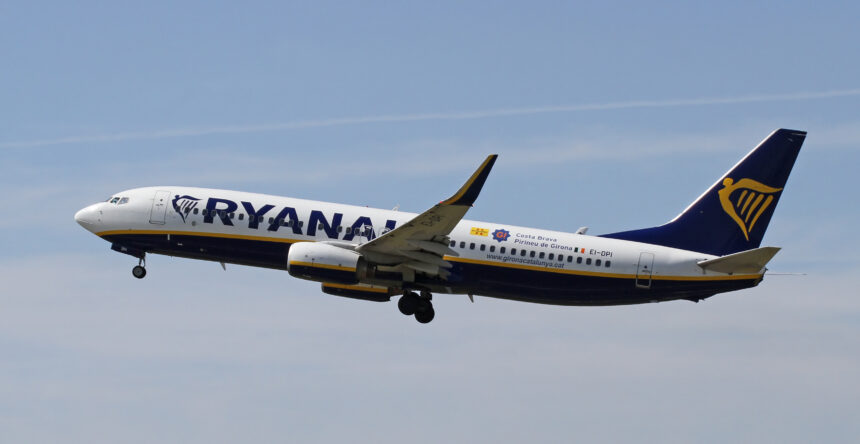 Ryanair Boeing 737 flying in blue sky; dispersing clouds in the background.