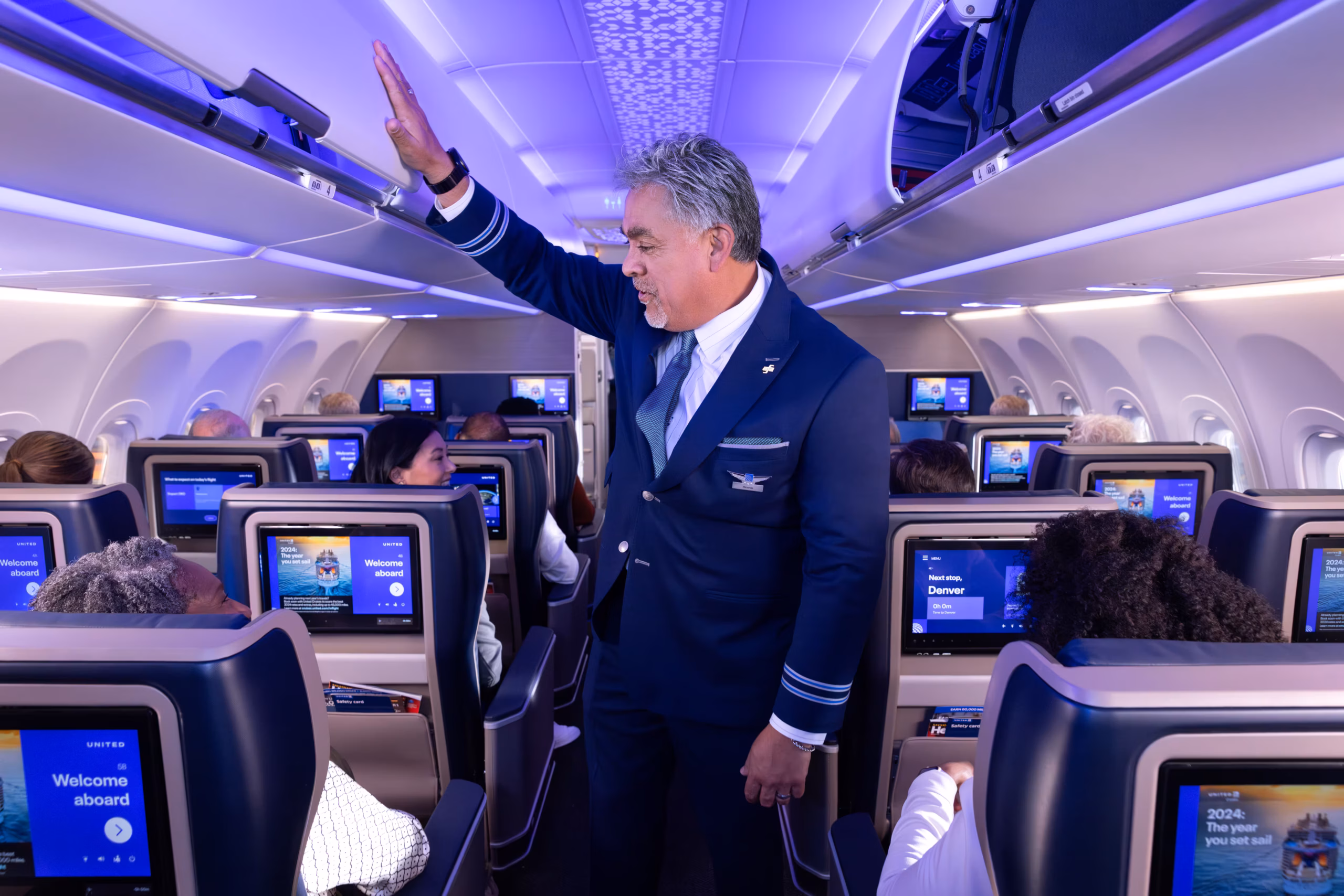 United Airlines flight attendant assisting passengers as airline enforces new headphone policy on flights