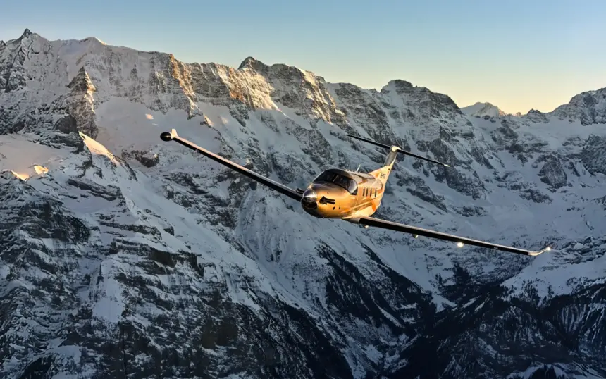 Pilatus PC-12 PRO aircraft flying through the snowy mountains.