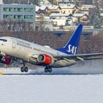 Scandinavian Airlines Boeing 737-700 landing on snowy ground.