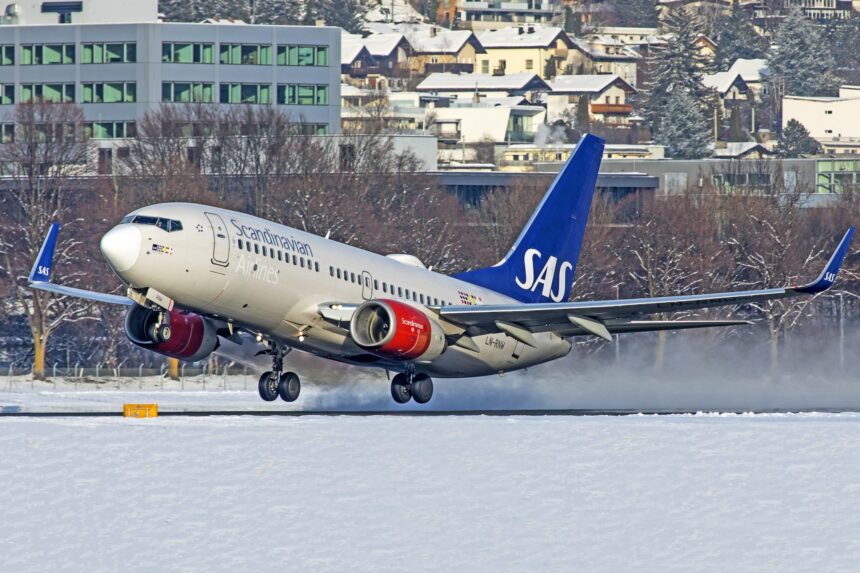 Scandinavian Airlines Boeing 737-700 landing on snowy ground.