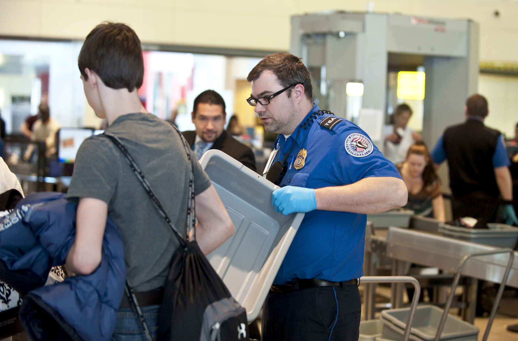 A TSA agent helps a passenger feed his luggage through the x-ray scanner at BWI's security checkpoint.