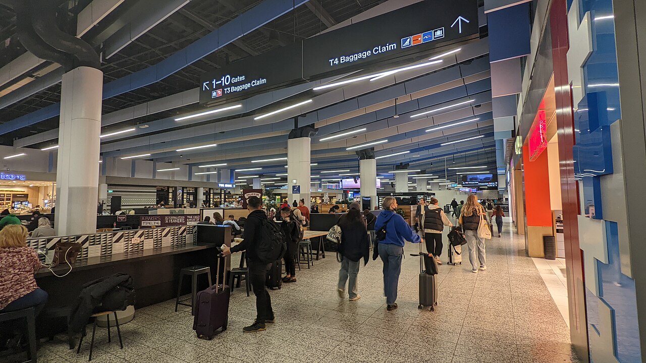 Terminal 4 interior at Melbourne Airport. People stood with luggage.