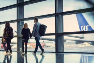 An image of people looking out of an airport window at a SAS aircraft