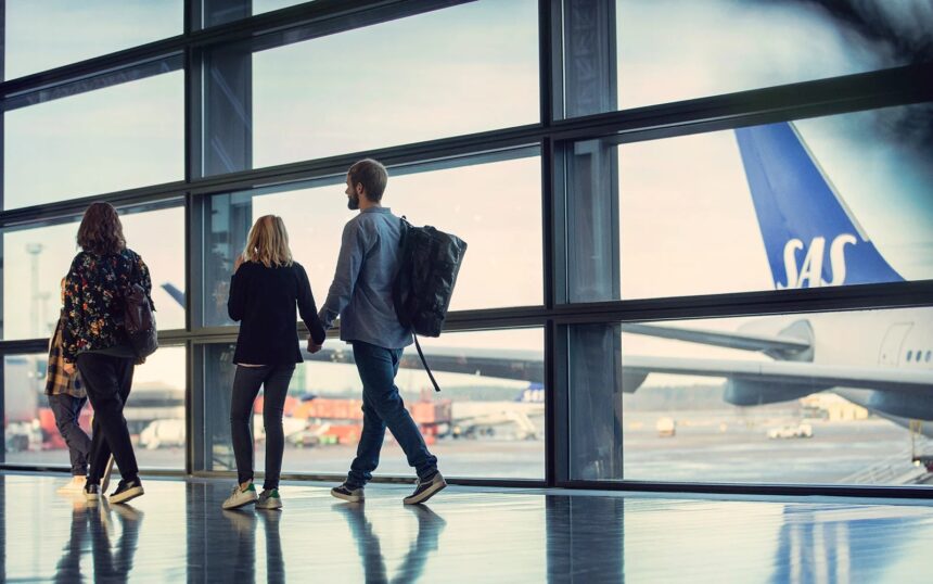 An image of people looking out of an airport window at a SAS aircraft