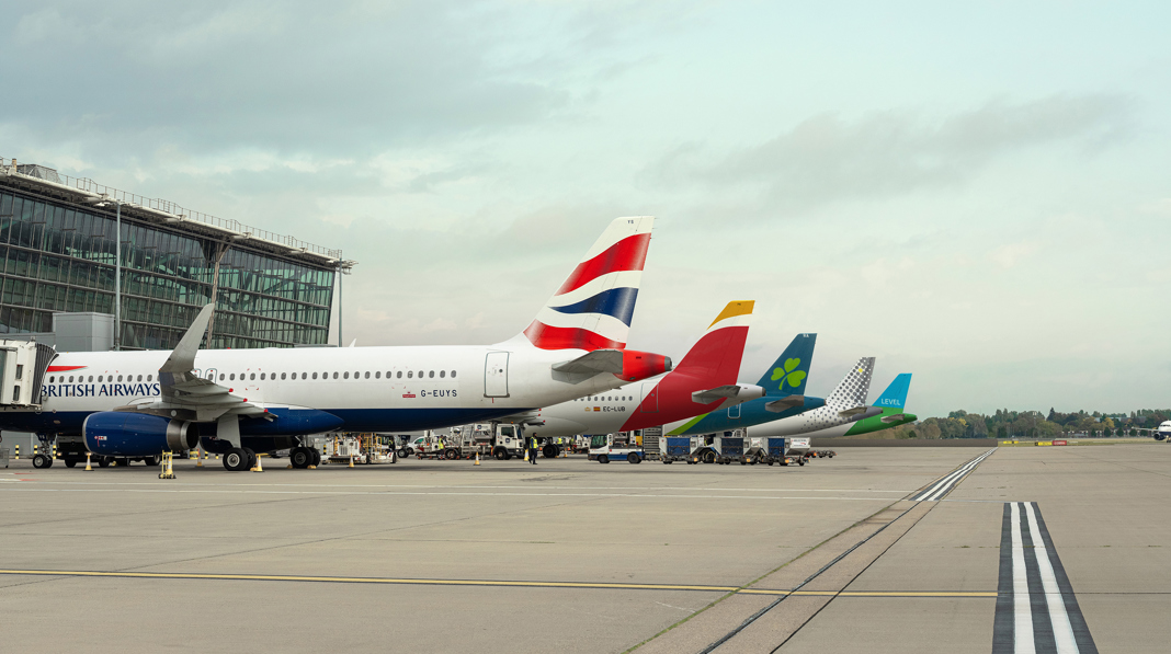 IAG group airline tail fins including British Airways, Iberia, Aer Lingus and LEVEL parked at an airport terminal