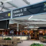 Image of Leeds Bradford Airport, signs showing gates and lounges above a large space in the airport.