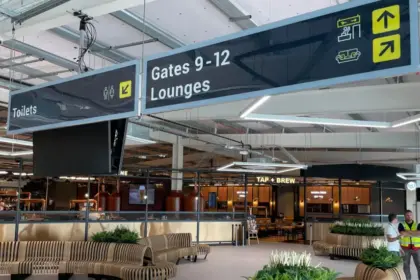 Image of Leeds Bradford Airport, signs showing gates and lounges above a large space in the airport.