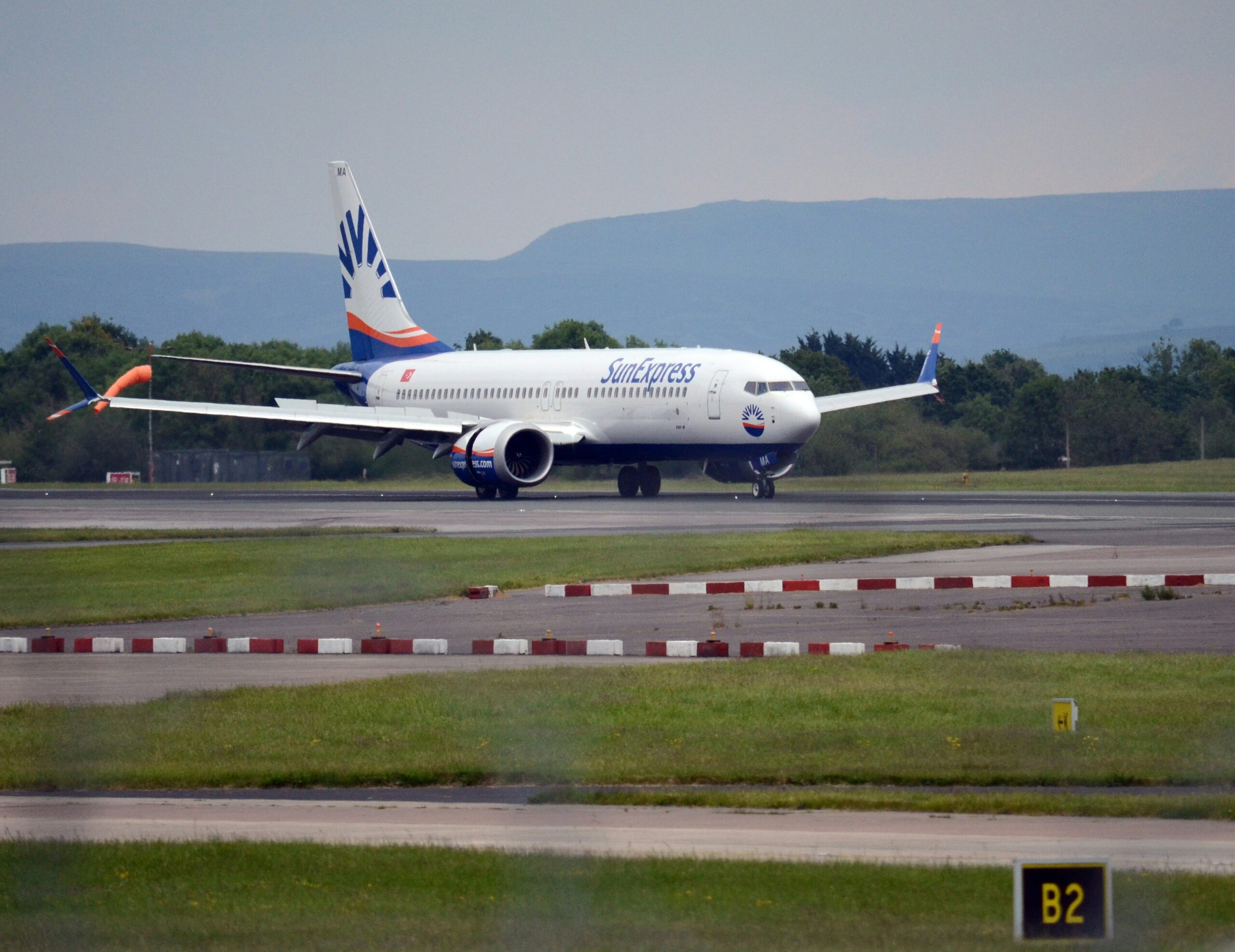 A large SunExpress jetliner landing on an airport runway.