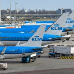 Several KLM airplanes parked at an airport terminal