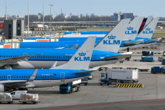 Several KLM airplanes parked at an airport terminal