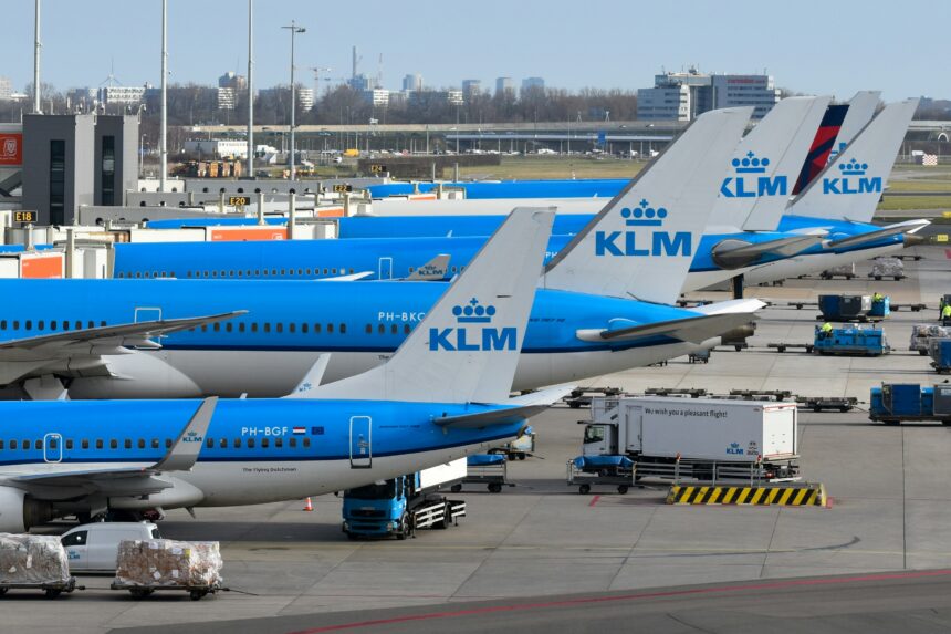 Several KLM airplanes parked at an airport terminal
