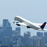 A Delta plane taking off, city in the background.
