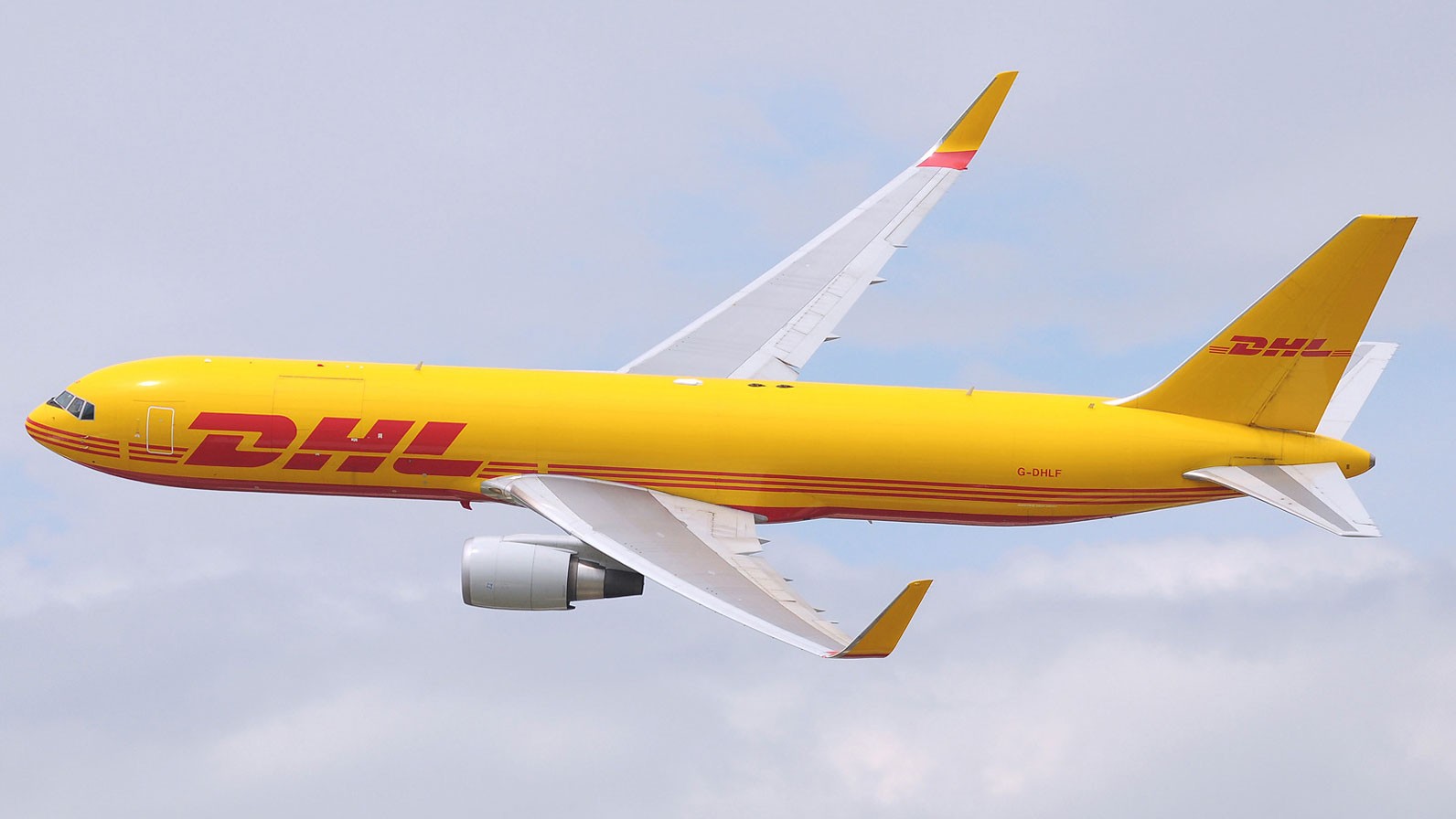 DHL Boeing aircraft, yellow and red livery, flying in the clouds.