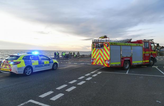 A police car and ambulance parked by the seafront