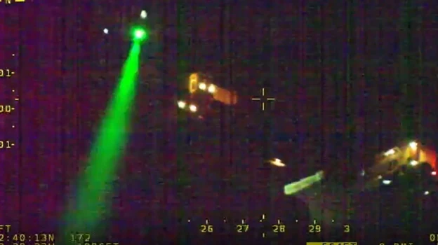 Aerial footage of a residential road showing a green laser coming from a house.