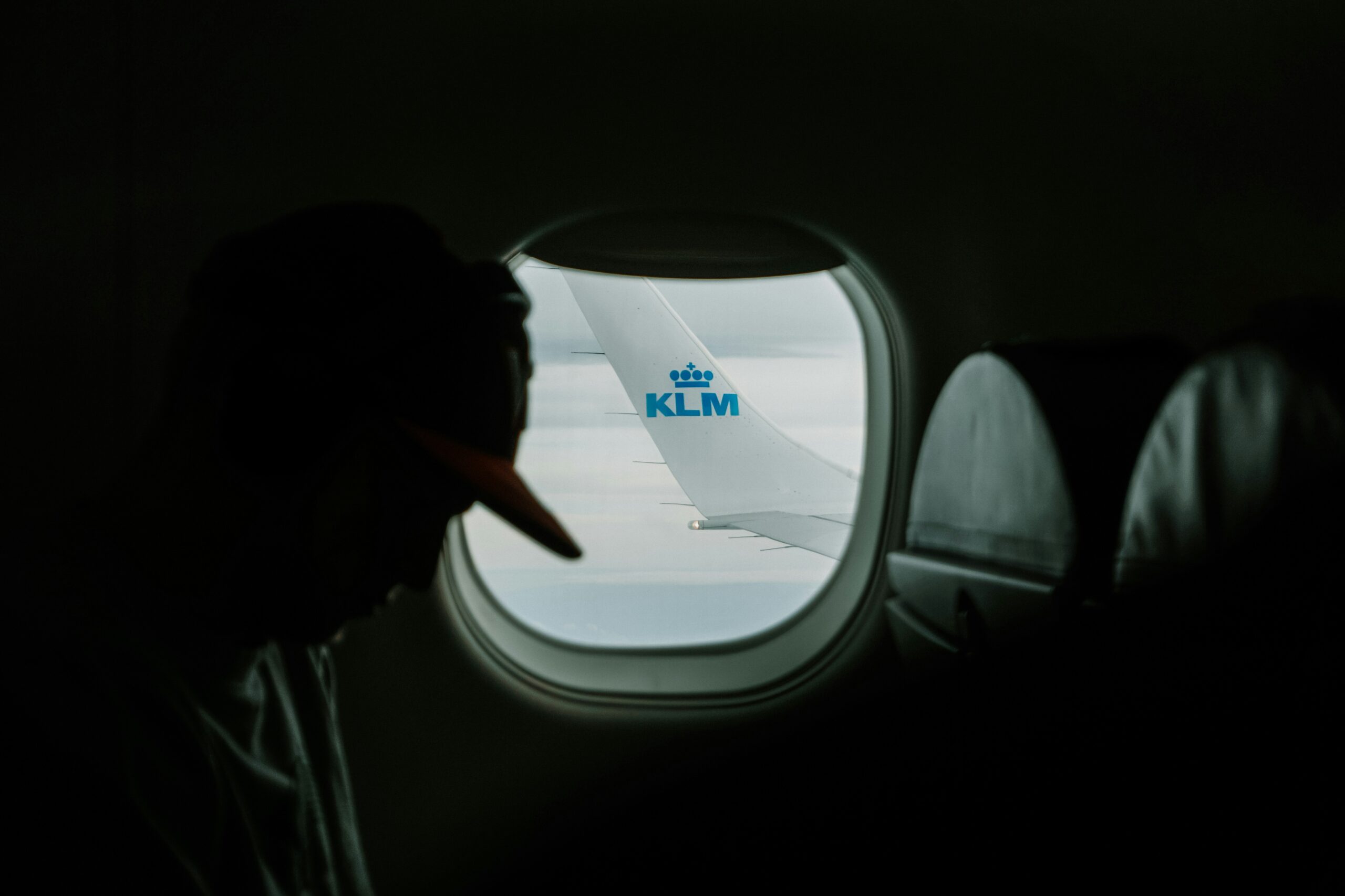 A man sitting at the window of a KLM airplane in flight