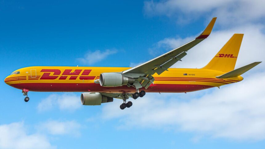 DHL Boeing aircraft flying in the sky. Blue sky and clouds in the background. Yellow livery.