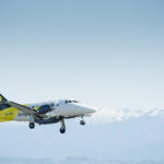 Originair aircraft flying under a blue sky