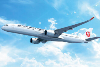 Japan Airlines A350-1000 in flight, pictured among blue skies with some clouds.