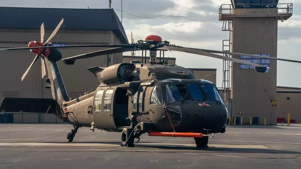 U.S. Black Hawk helicopter on the ground with long turbines and a green exterior.