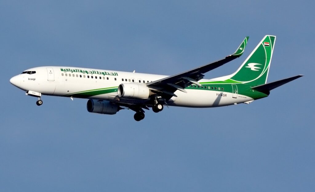 An Iraqi Airways Boeing 737-800 in white photographed on approach with landing gear deployed.
