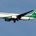 An Iraqi Airways Boeing 737-800 in white photographed on approach with landing gear deployed.