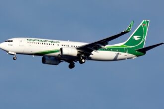 An Iraqi Airways Boeing 737-800 in white photographed on approach with landing gear deployed.