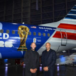 Tim Howard and Thierry Henry pose in front of American Airlines' FIFA World Cup 26-themed aircraft livery